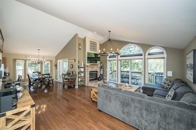 living room with a fireplace, hardwood / wood-style floors, high vaulted ceiling, and an inviting chandelier