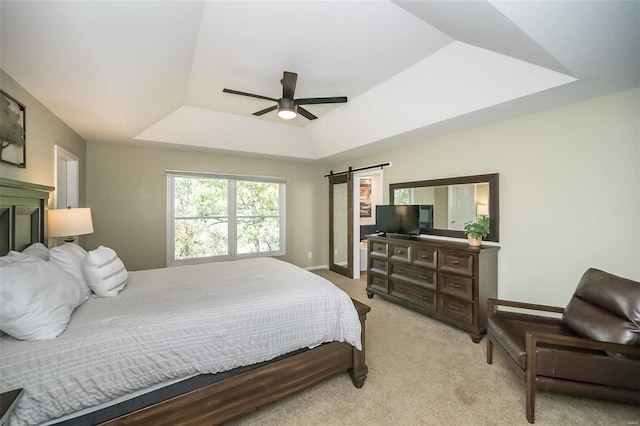 carpeted bedroom featuring ceiling fan, a barn door, and a tray ceiling