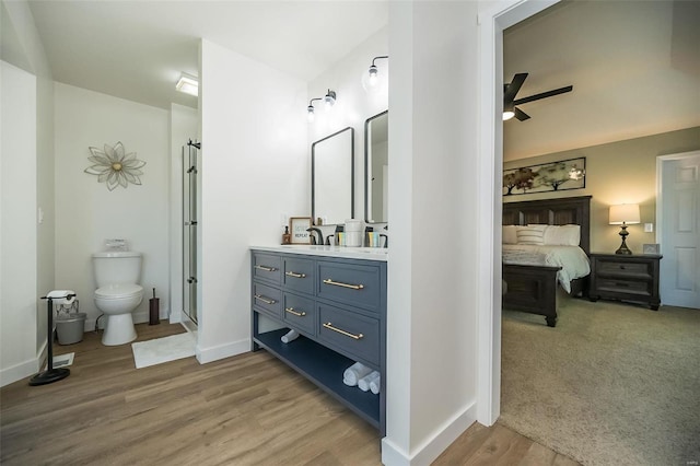 bathroom featuring hardwood / wood-style floors, vanity, ceiling fan, toilet, and walk in shower