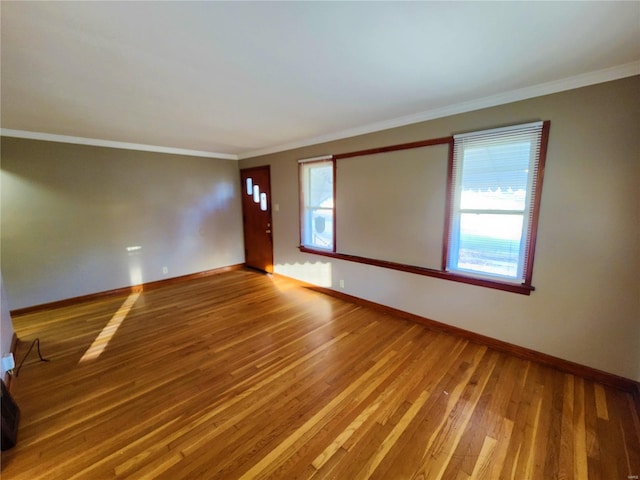 empty room with hardwood / wood-style flooring, plenty of natural light, and ornamental molding