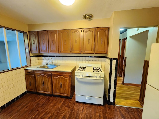 kitchen with tile walls, white appliances, sink, and dark wood-type flooring