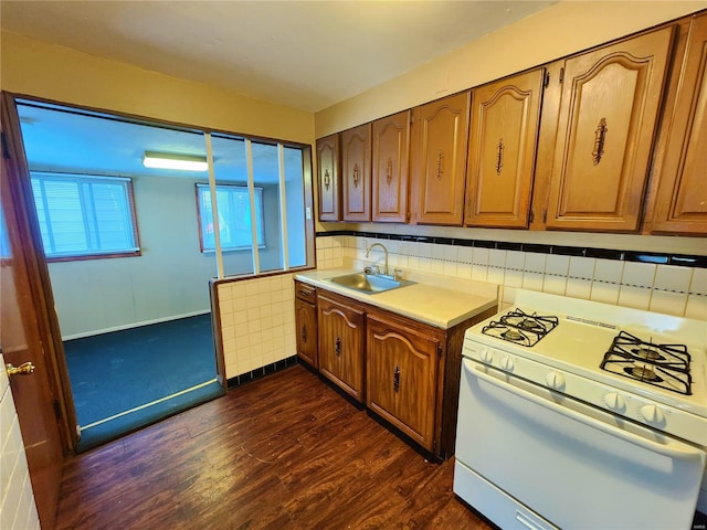 kitchen featuring decorative backsplash, dark hardwood / wood-style floors, white gas range, and sink