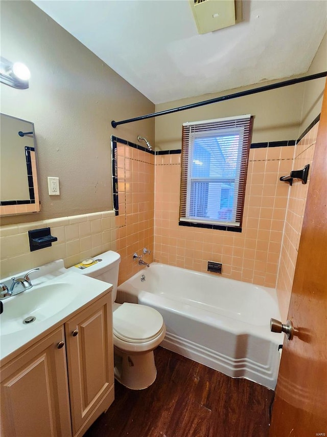 full bathroom featuring vanity, hardwood / wood-style flooring, tile walls, toilet, and tiled shower / bath