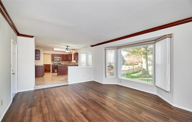 unfurnished living room with ceiling fan, ornamental molding, and dark wood-type flooring