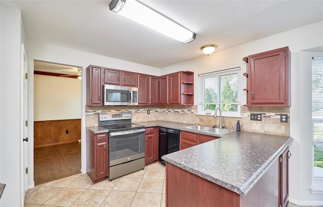 kitchen with decorative backsplash, kitchen peninsula, stainless steel appliances, sink, and light tile patterned floors