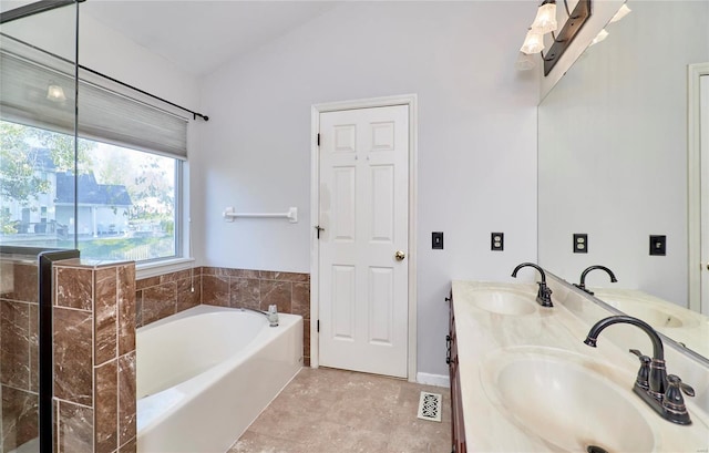 bathroom with vanity, a bath, and vaulted ceiling