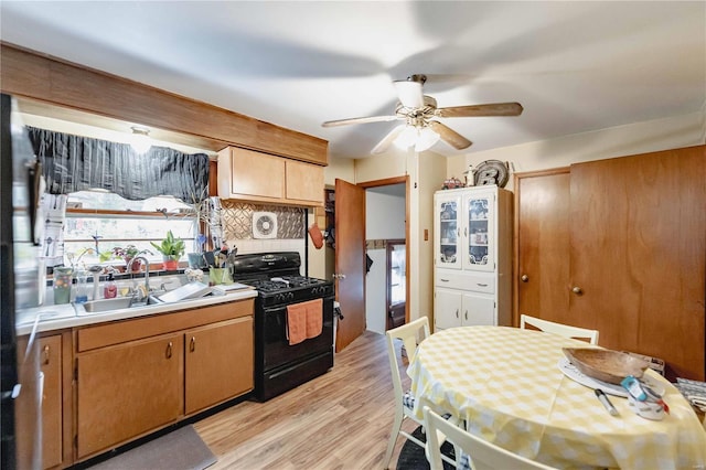 kitchen featuring sink, ceiling fan, light hardwood / wood-style floors, tasteful backsplash, and gas stove