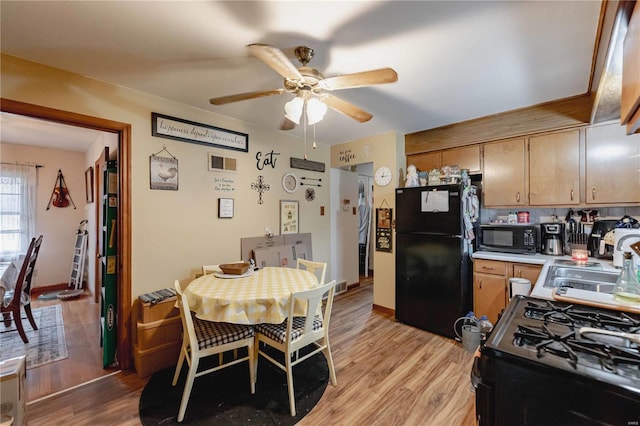 dining area featuring ceiling fan, sink, and light wood-type flooring