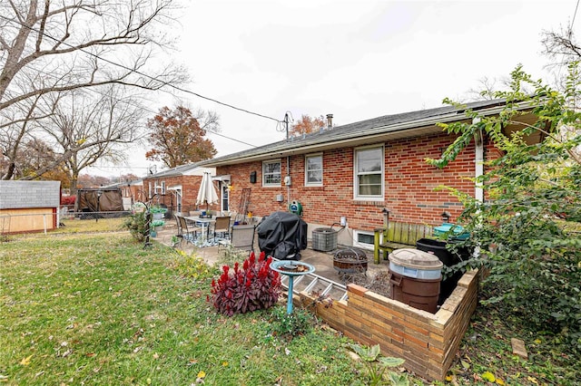 back of house with cooling unit, a patio area, a yard, and an outdoor fire pit