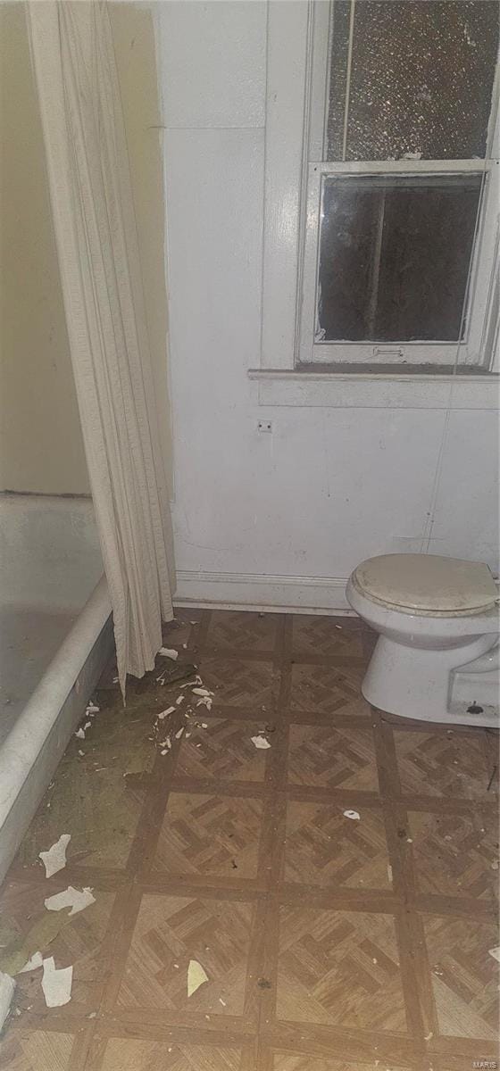 bathroom featuring toilet and parquet flooring