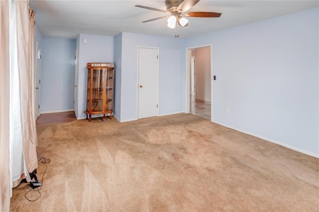 empty room featuring ceiling fan and light colored carpet