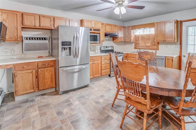 kitchen with light brown cabinets, sink, ceiling fan, appliances with stainless steel finishes, and a wall unit AC