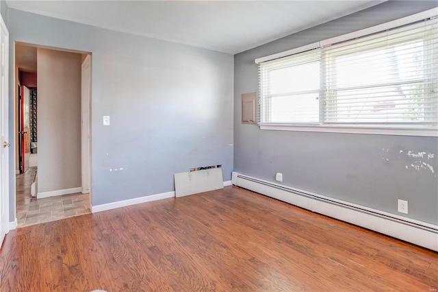 unfurnished room featuring a wealth of natural light, baseboard heating, and wood-type flooring