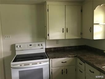 kitchen with white electric range oven and dark stone countertops