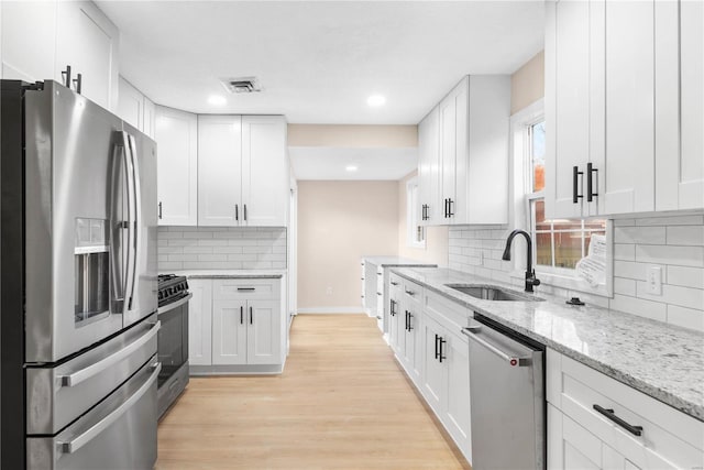 kitchen featuring white cabinets, appliances with stainless steel finishes, light wood-type flooring, and sink