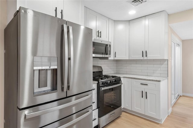 kitchen featuring white cabinets, light stone counters, light wood-type flooring, and appliances with stainless steel finishes