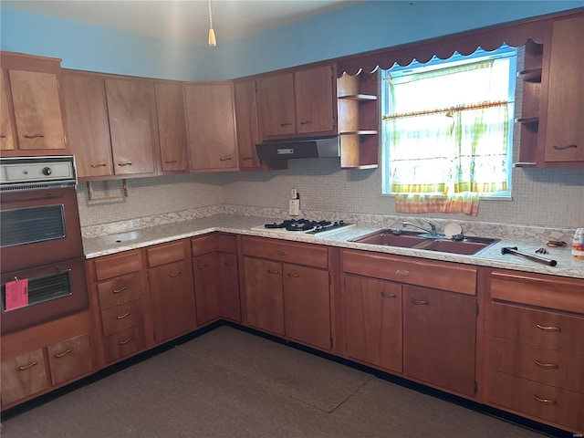 kitchen featuring decorative backsplash, white gas cooktop, sink, dark tile patterned flooring, and black oven