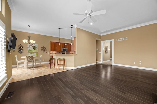 unfurnished living room with ceiling fan with notable chandelier, dark hardwood / wood-style floors, and crown molding