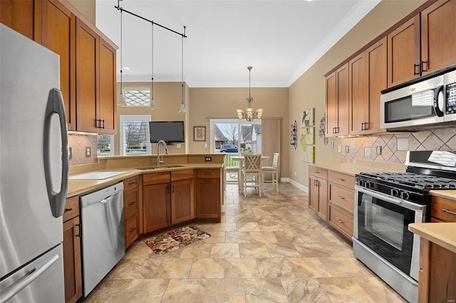 kitchen featuring appliances with stainless steel finishes, ornamental molding, sink, decorative light fixtures, and an inviting chandelier