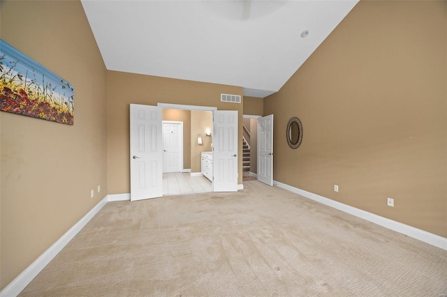 unfurnished bedroom with light carpet and high vaulted ceiling