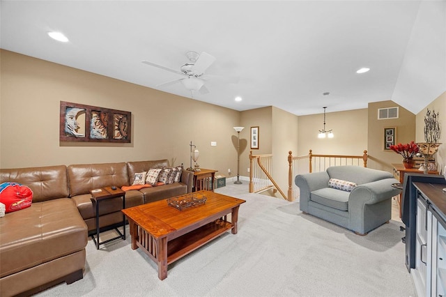 carpeted living room with ceiling fan with notable chandelier