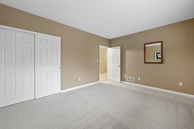 unfurnished bedroom with light colored carpet and a closet