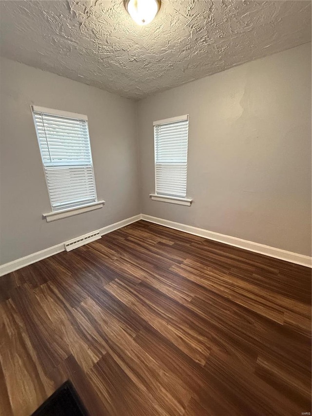 unfurnished room featuring a textured ceiling, plenty of natural light, and dark wood-type flooring