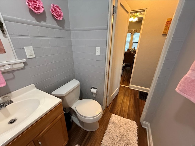 bathroom with hardwood / wood-style floors, vanity, toilet, and tile walls