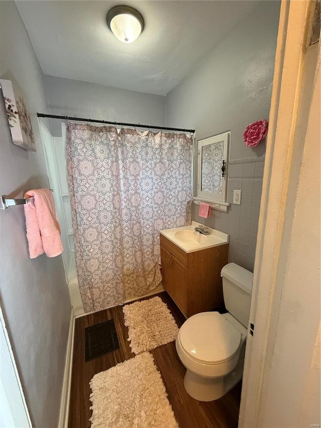 full bathroom featuring vanity, wood-type flooring, shower / bathtub combination with curtain, tile walls, and toilet