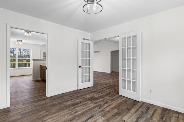 spare room featuring french doors, dark wood-style flooring, visible vents, a chandelier, and baseboards