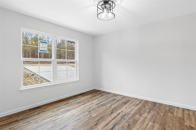 unfurnished room with visible vents, wood finished floors, and a wealth of natural light