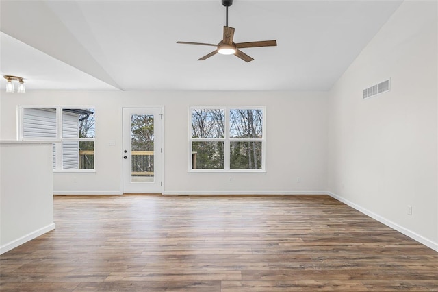 empty room with ceiling fan, visible vents, vaulted ceiling, and wood finished floors