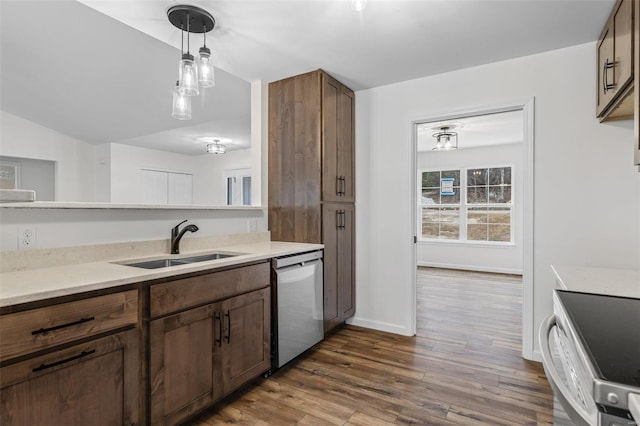 kitchen featuring dark wood-style floors, decorative light fixtures, a sink, dishwasher, and baseboards