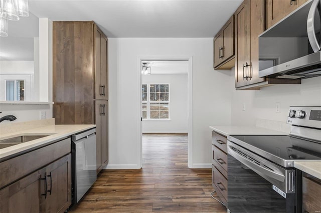 kitchen featuring dark wood-style floors, stainless steel appliances, a sink, and light countertops