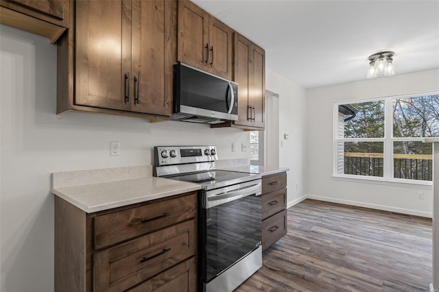 kitchen with light countertops, appliances with stainless steel finishes, dark wood-type flooring, and baseboards