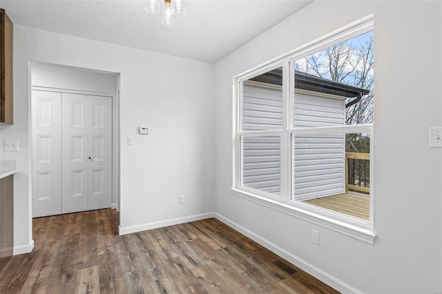 unfurnished dining area featuring visible vents, baseboards, and wood finished floors