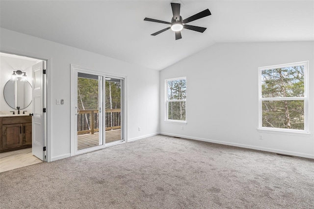 unfurnished room featuring light carpet, a sink, a ceiling fan, baseboards, and vaulted ceiling