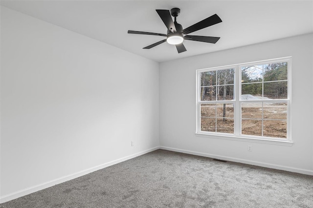 carpeted spare room with a ceiling fan, visible vents, and baseboards