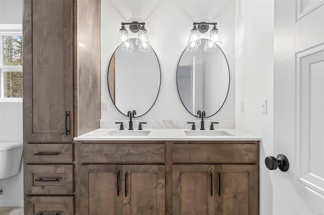 full bathroom with toilet, double vanity, and a sink