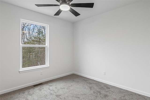 spare room with carpet floors, a ceiling fan, visible vents, and baseboards