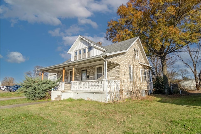 bungalow-style home with covered porch, a chimney, and a front lawn