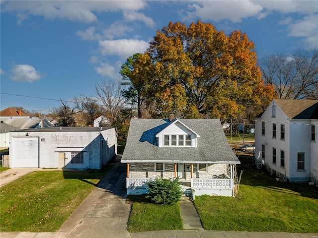 view of front of house featuring stone siding, driveway, covered porch, and a front yard