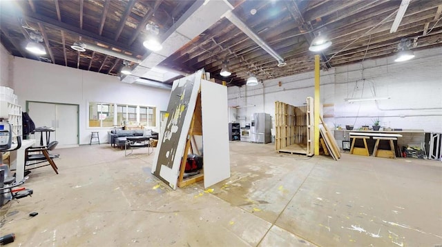 basement with stainless steel fridge and a workshop area