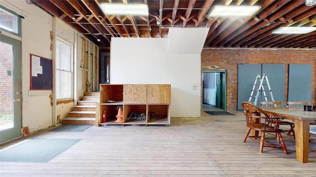 interior space featuring a wealth of natural light, brick wall, and light wood-type flooring