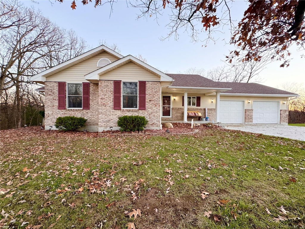 single story home with covered porch, a garage, and a front lawn