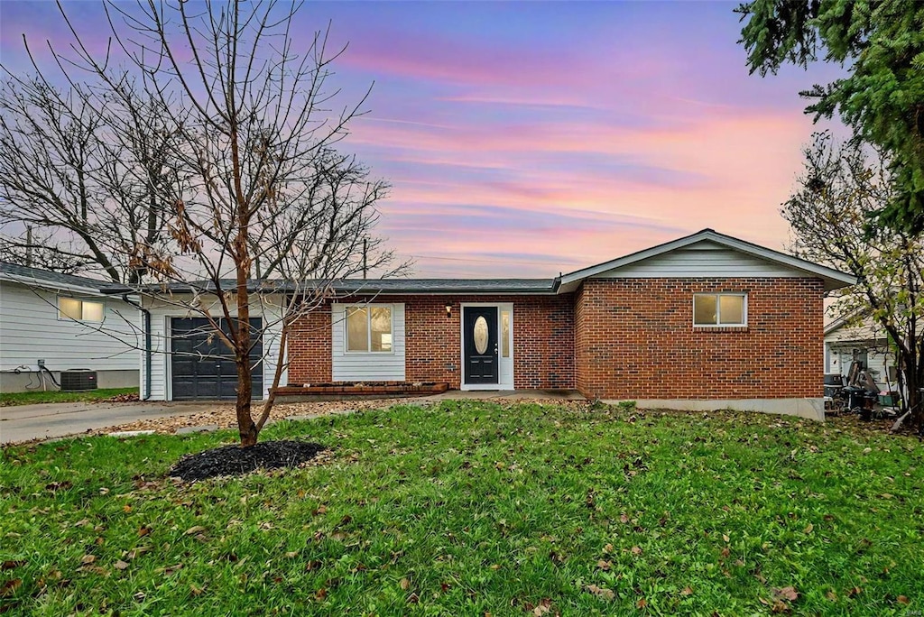 single story home with a lawn, central AC unit, and a garage