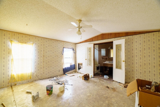 interior space with ceiling fan, a textured ceiling, connected bathroom, and vaulted ceiling