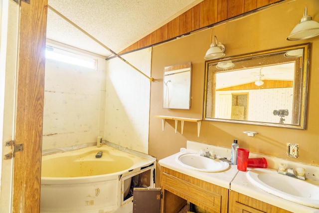 bathroom featuring a bath, a textured ceiling, and vaulted ceiling