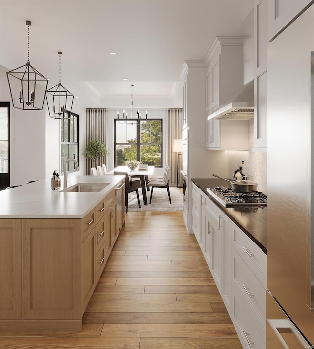 kitchen with a large island with sink, white cabinets, stainless steel appliances, and light hardwood / wood-style floors