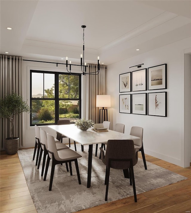 dining area featuring a tray ceiling, a notable chandelier, and light wood-type flooring